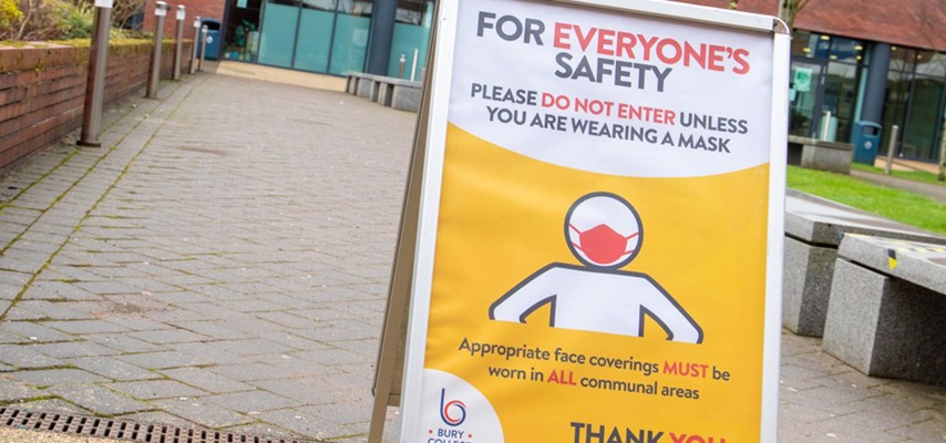 An A-board instructing students that they must wear a mask before entering a building