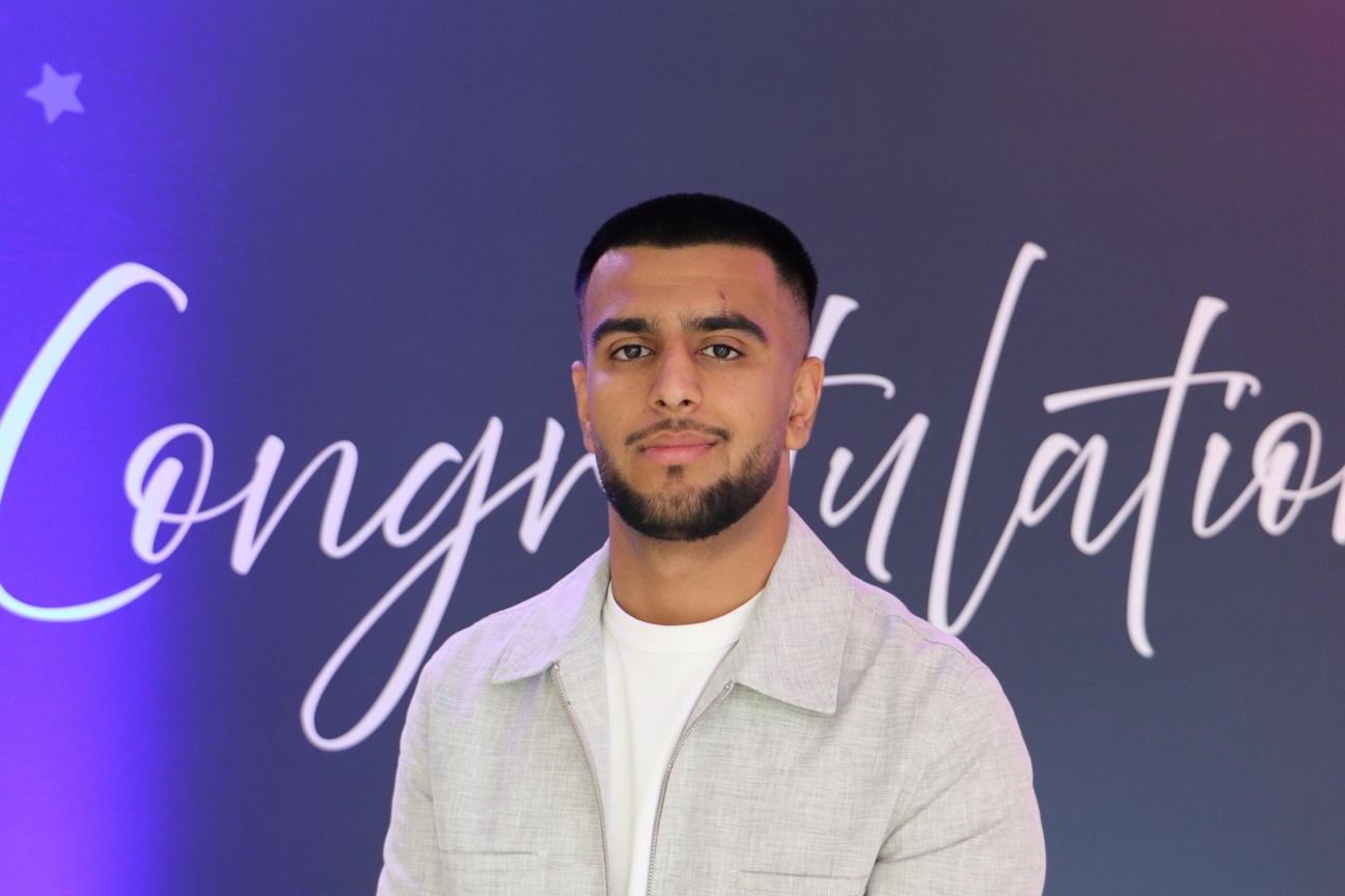 student stood in front of congratulations sign