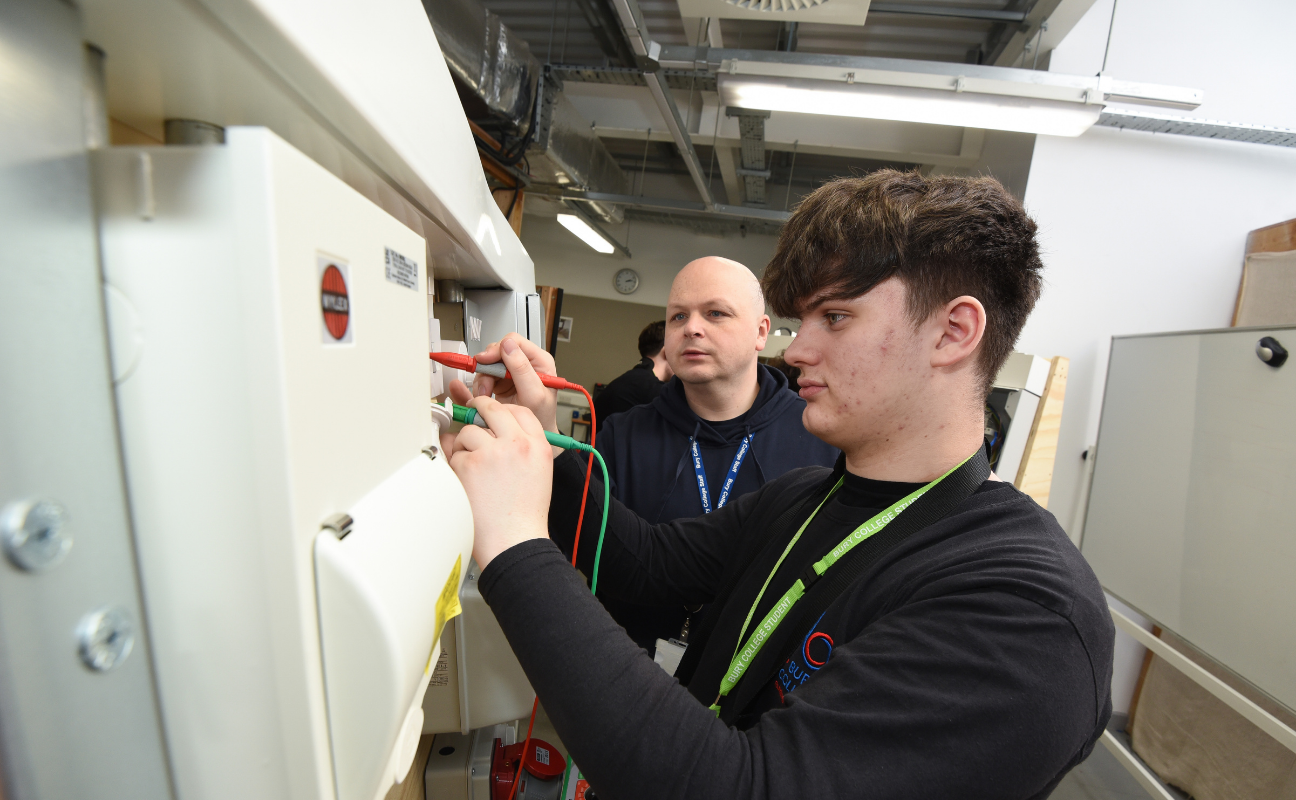 electrical installation student working on an electrical unit with the support of a teacher