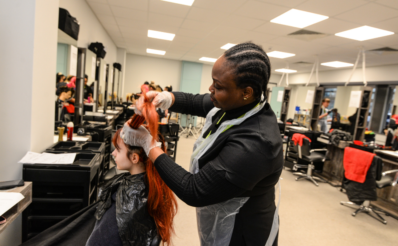 Adult learner taking part in a practical hairdressing lesson in the salon