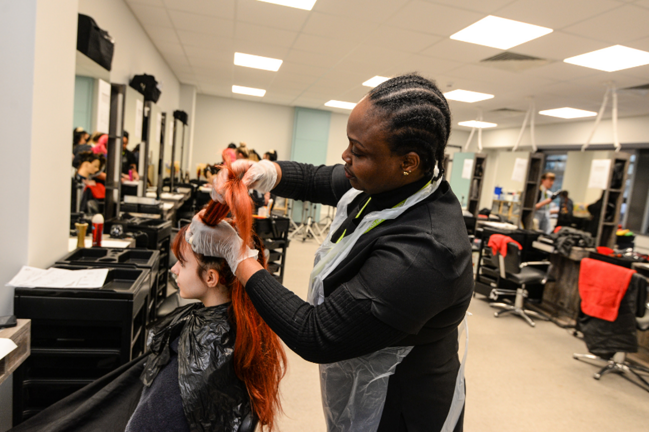 Adult learner taking part in a practical hairdressing lesson in the salon
