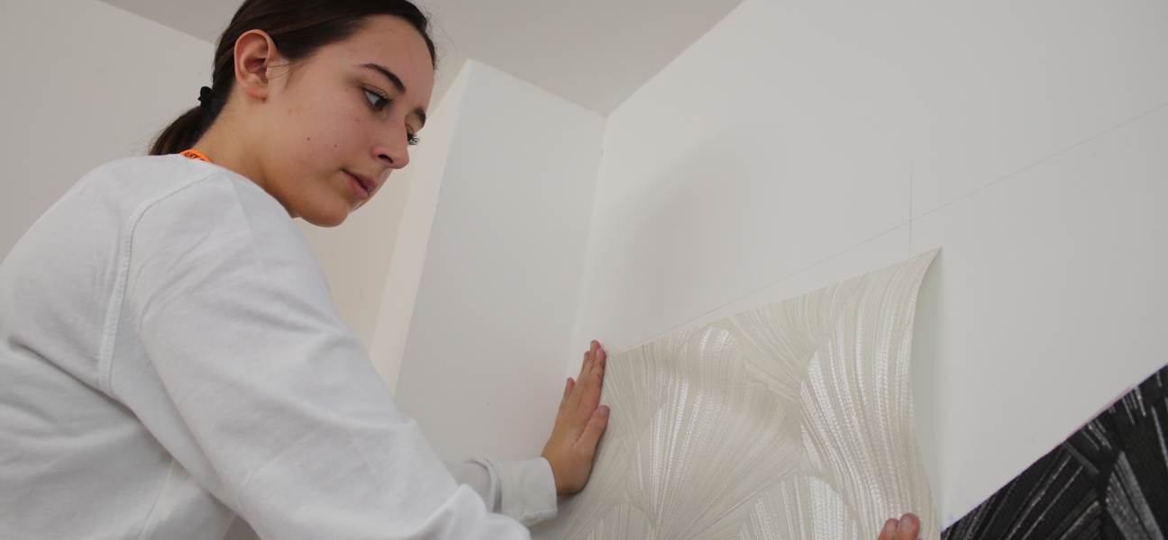 painting and decorating student applying wallpaper
