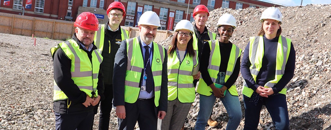 Deputy Principal, Andrew Harrison stood with a group of people wearing high visibility vests on a construction site