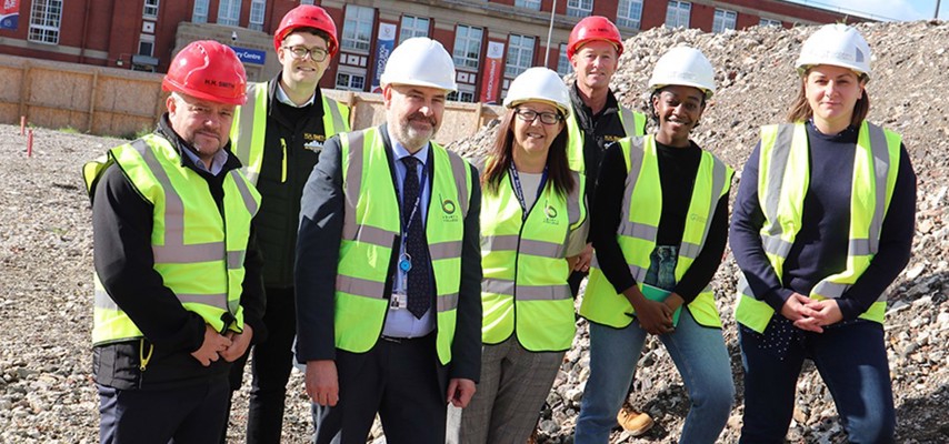 Deputy Principal, Andrew Harrison stood with a group of people wearing high visibility vests on a construction site