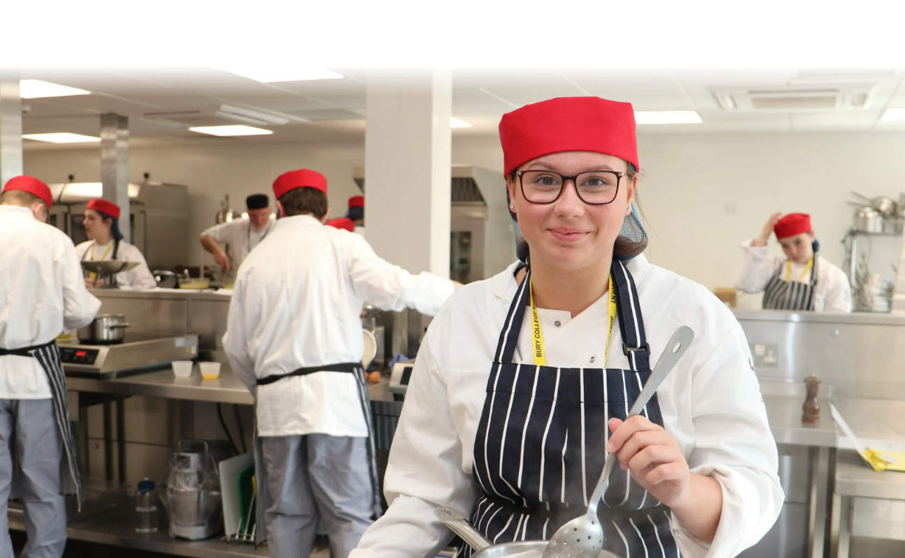 catering student stirring something in a pan whilst smiling
