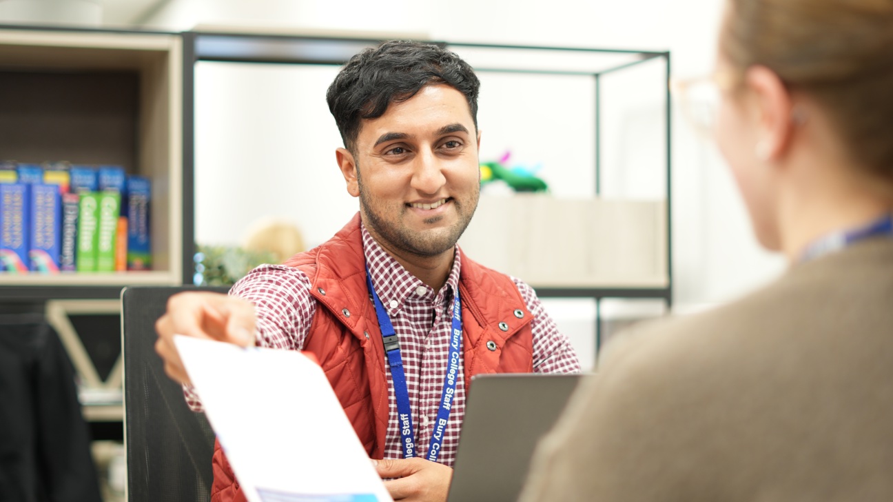 staff member handing a leaflet to a student