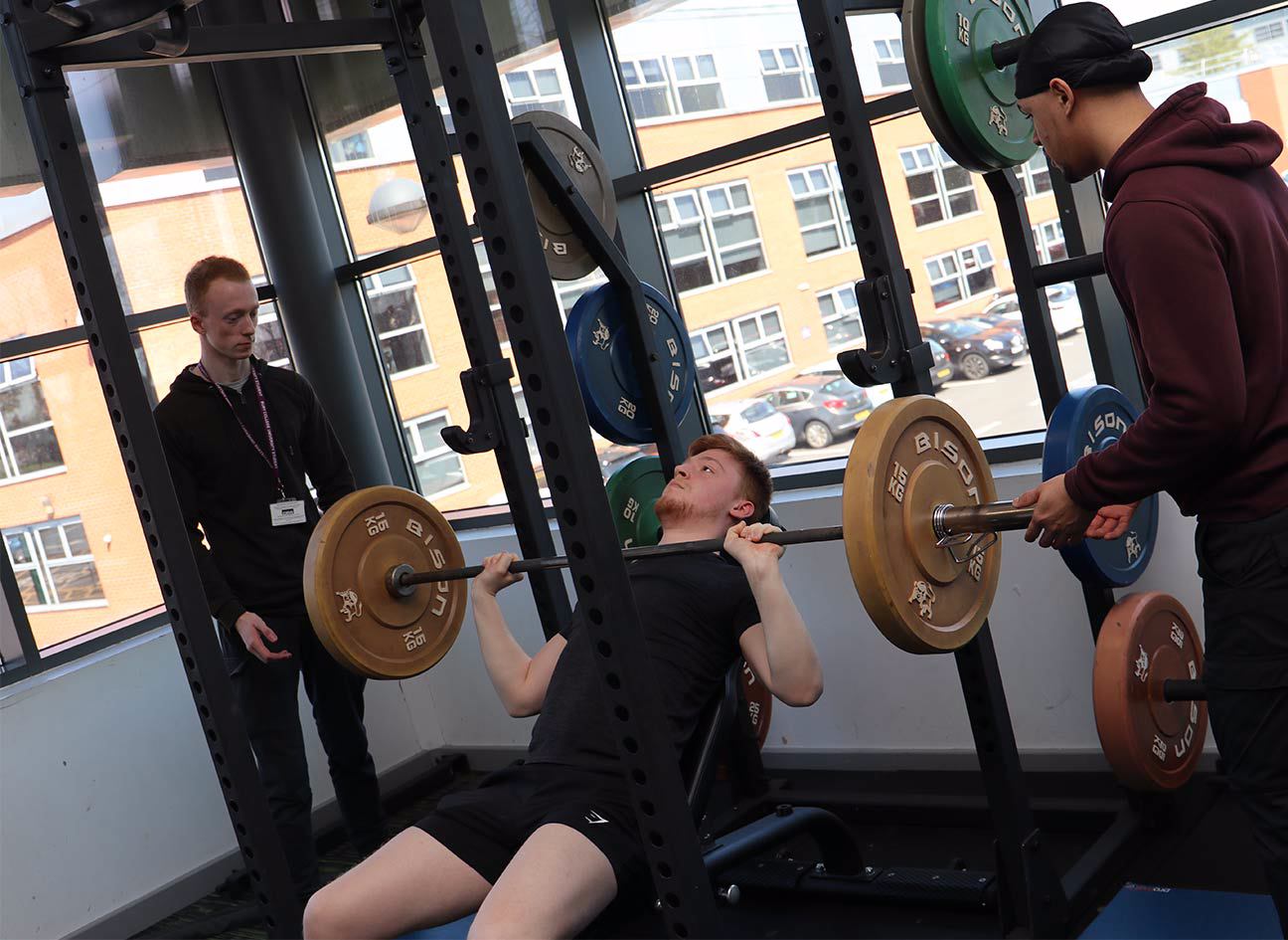 Student using the bench-press machine in the gym