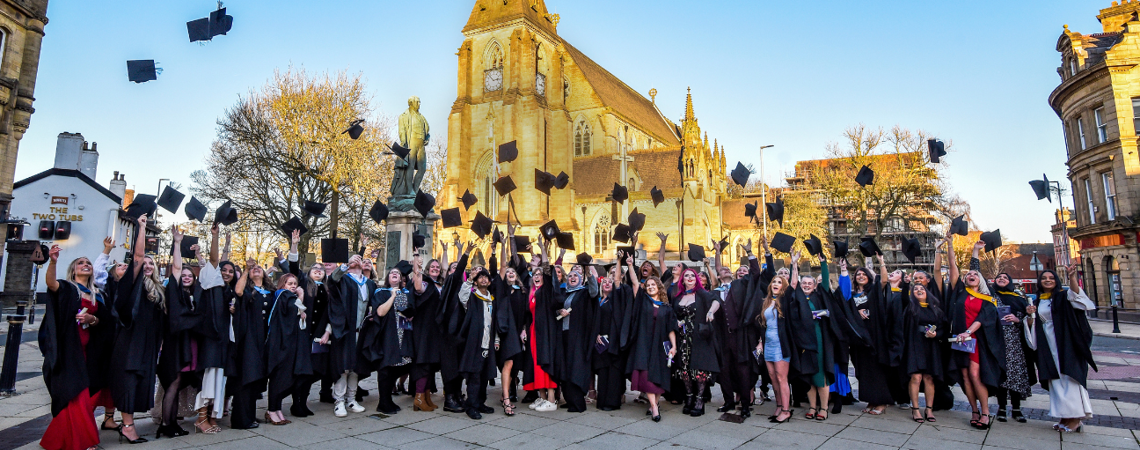 graduates throwing their caps into the air in celebration