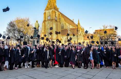 graduates throwing their caps into the air in celebration