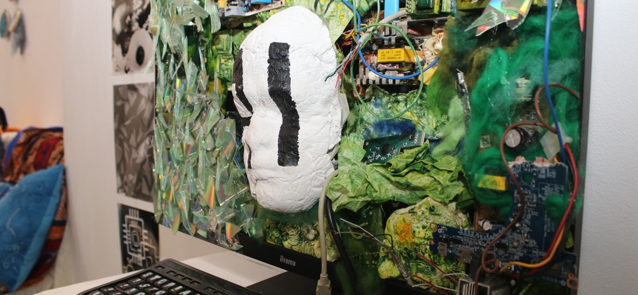 a mask of a face breaking out of a computer screen