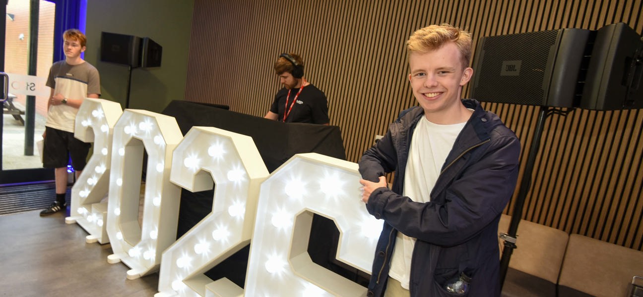 student stood in front of 2026 light up letters