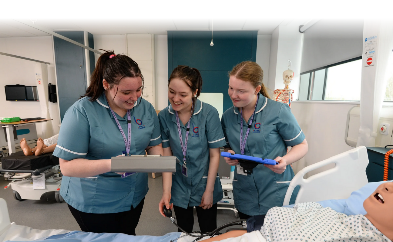 Health and Social care students stood analysing data in the mock ward