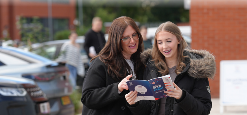 student and parent stood looking at an open event guide