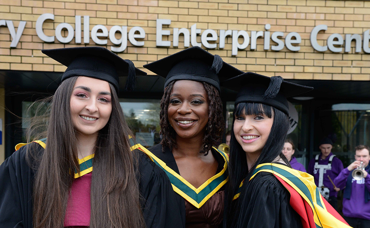 Three graduates smiling to camera