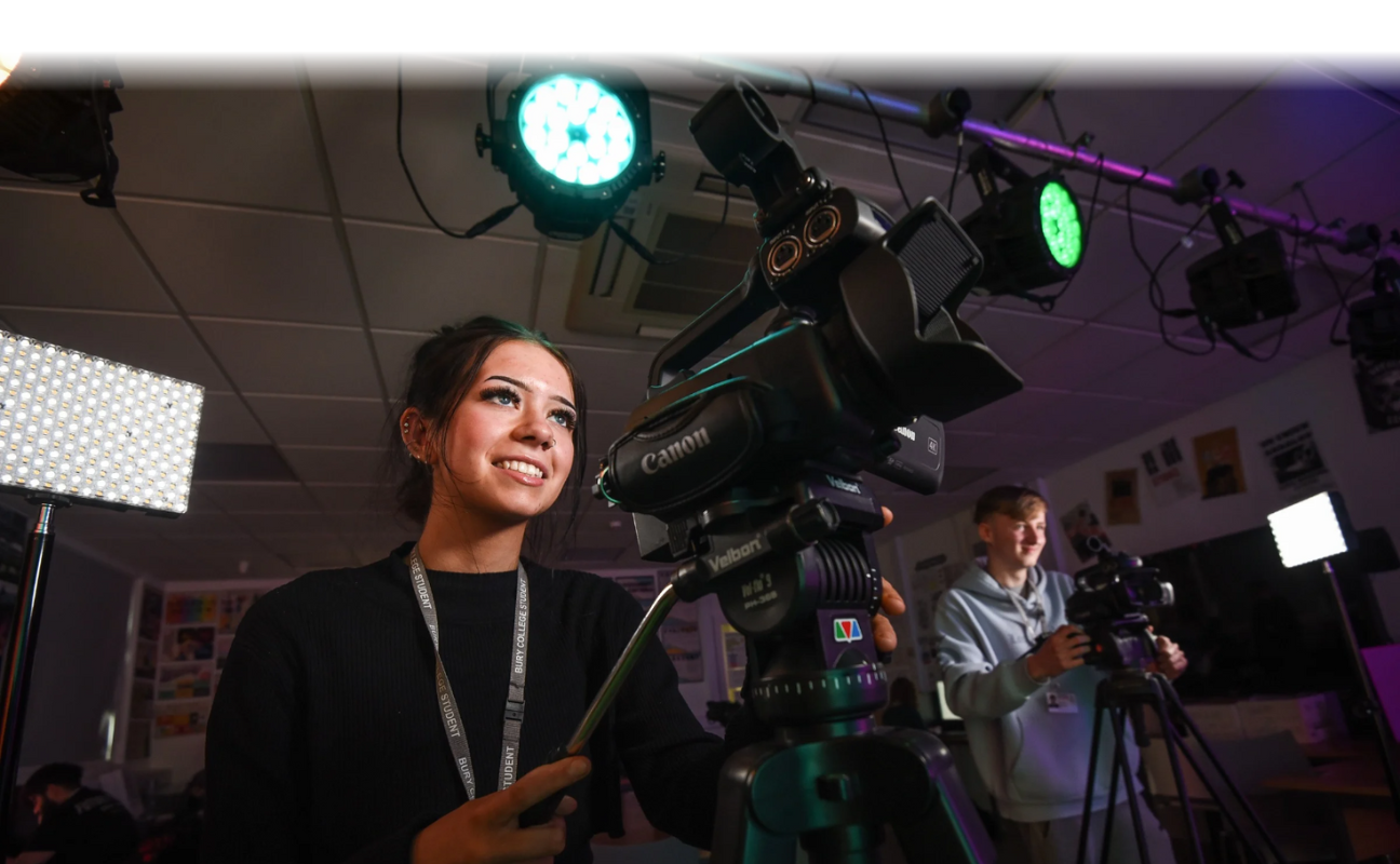 media student in a classroom operating a camera