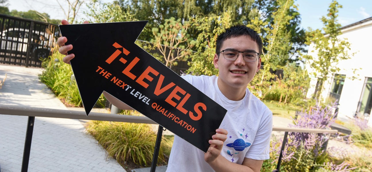 student holding a t level sign