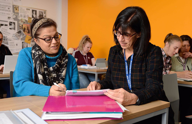 University student and tutor chatting to each other in a classroom