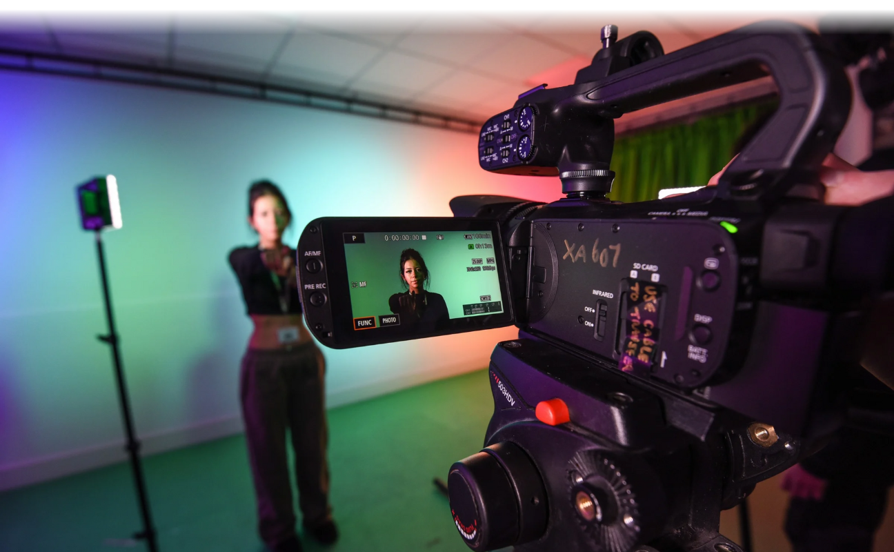 media student posing in front of a camera stood against a green screen