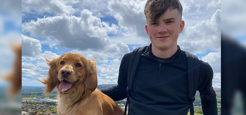 Former Bury College A-level student, Adam Kenzitt, sat on a hill with a dog