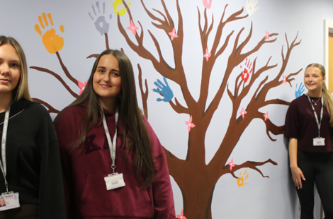 art students stood in front of tree mural
