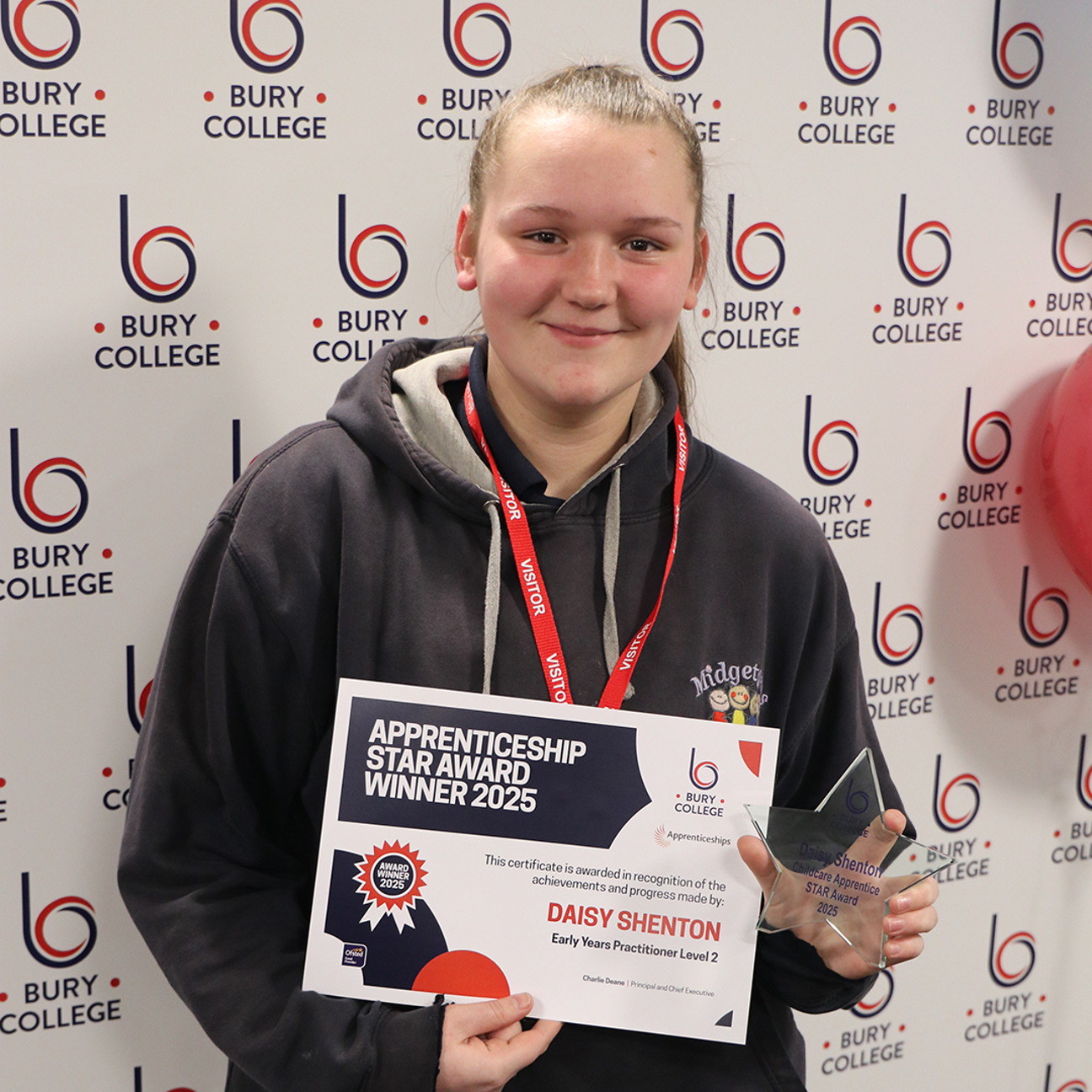 student holding glass trophy and certificate