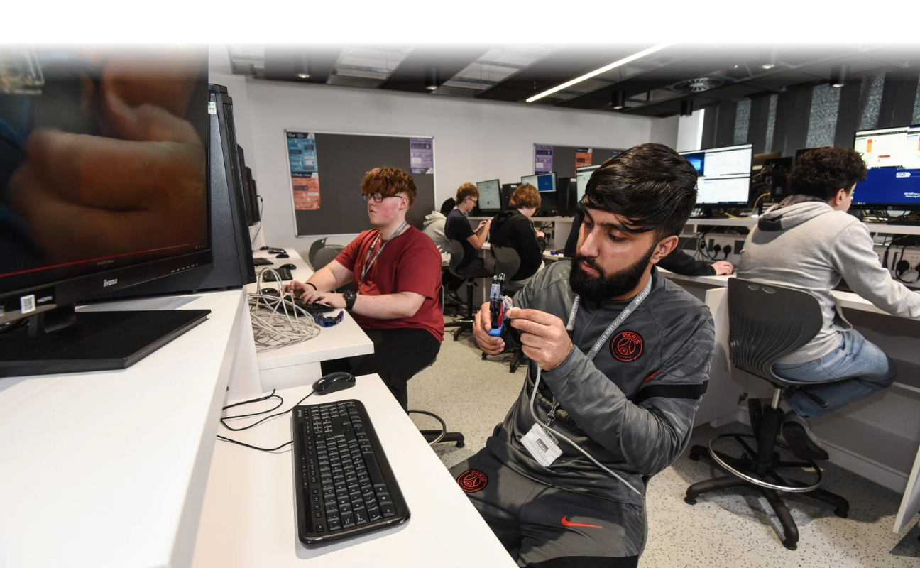 computing student sat in an IT suite holding a device