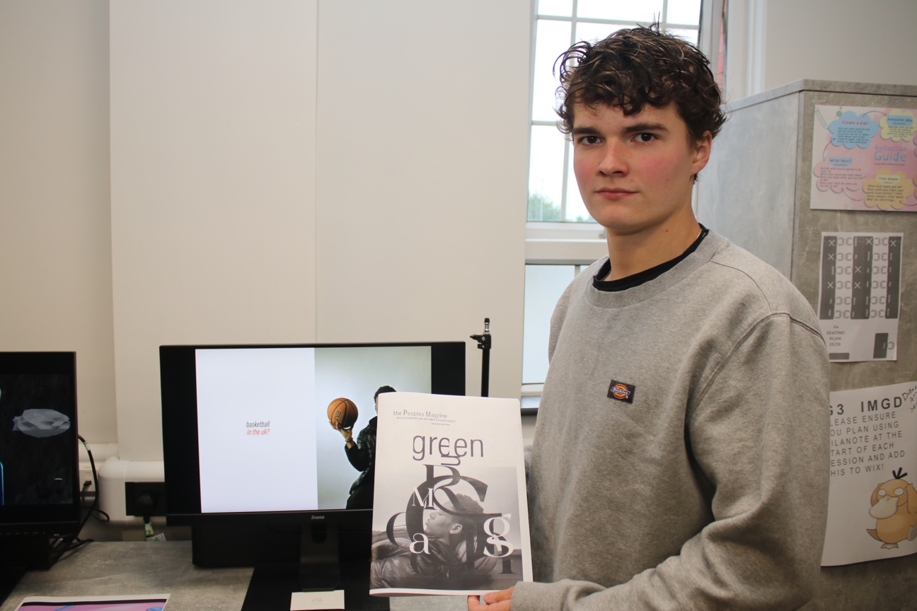 a student stood holding a basketball magazine they designed
