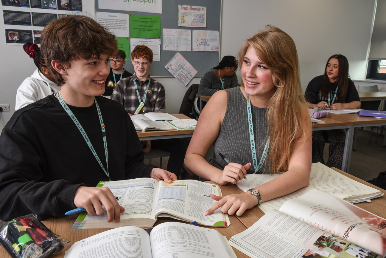 two students sat in a classroom talking about work