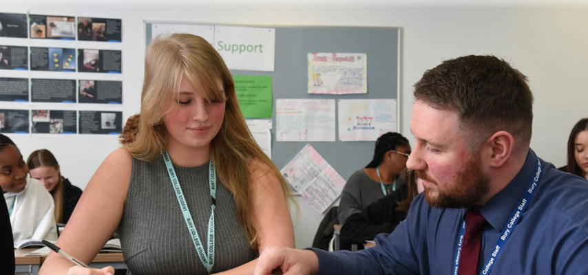 student sat in a classroom with the support of teacher