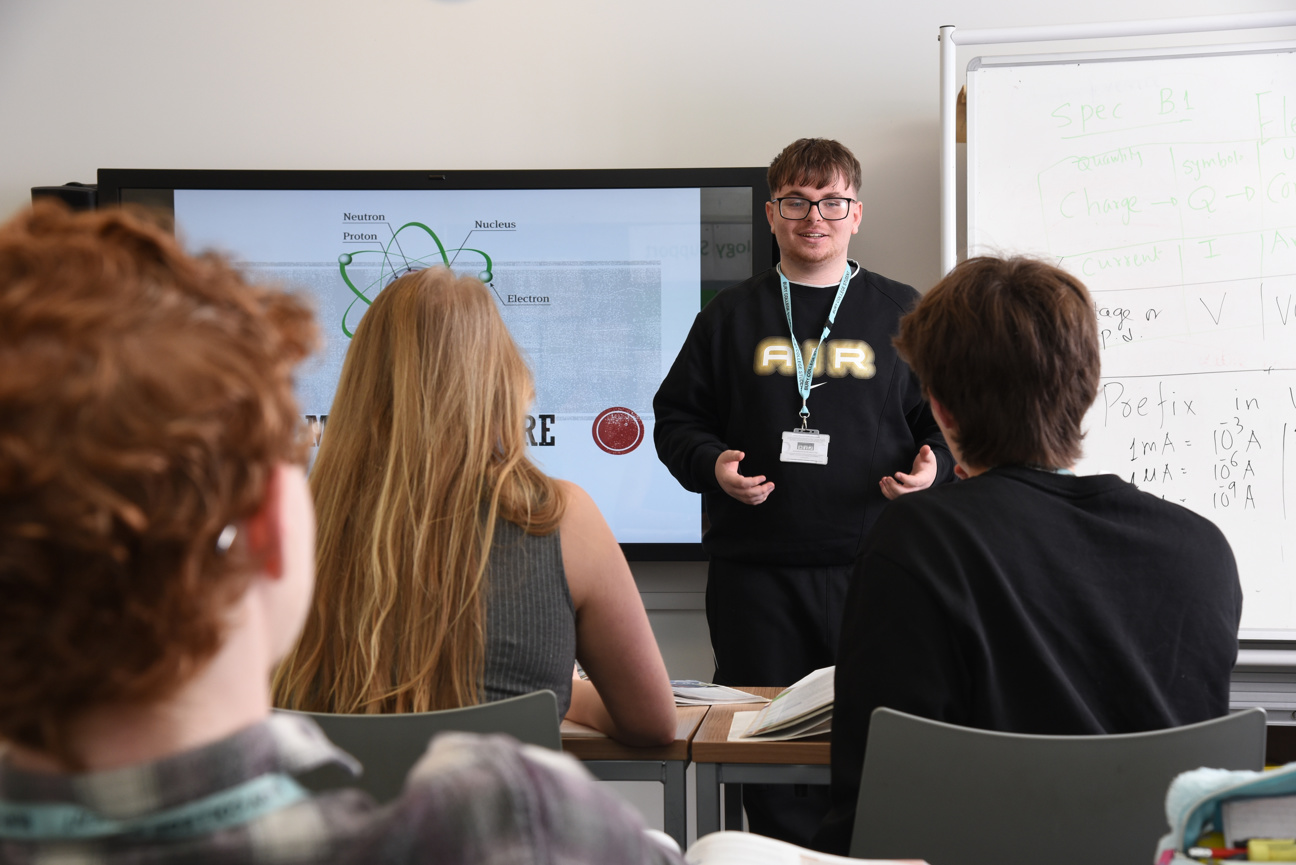 student stood presenting at the front of a classroom