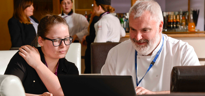 Bury College catering student sat with a Catering staff member in the 3 seasons restaurant