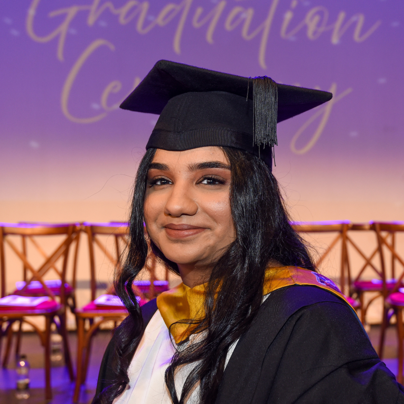 student on their graduation day sat in front of the stage