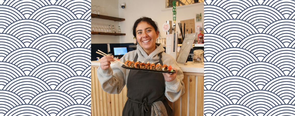 owner of codi's kitchen stood holding a plate of sushi