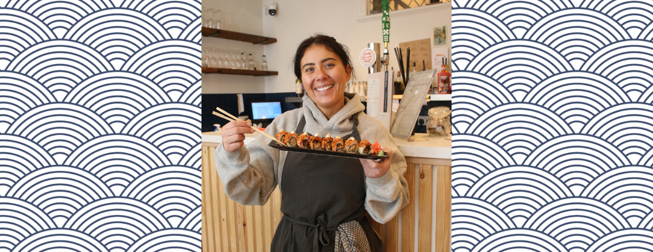 owner of codi's kitchen stood holding a plate of sushi