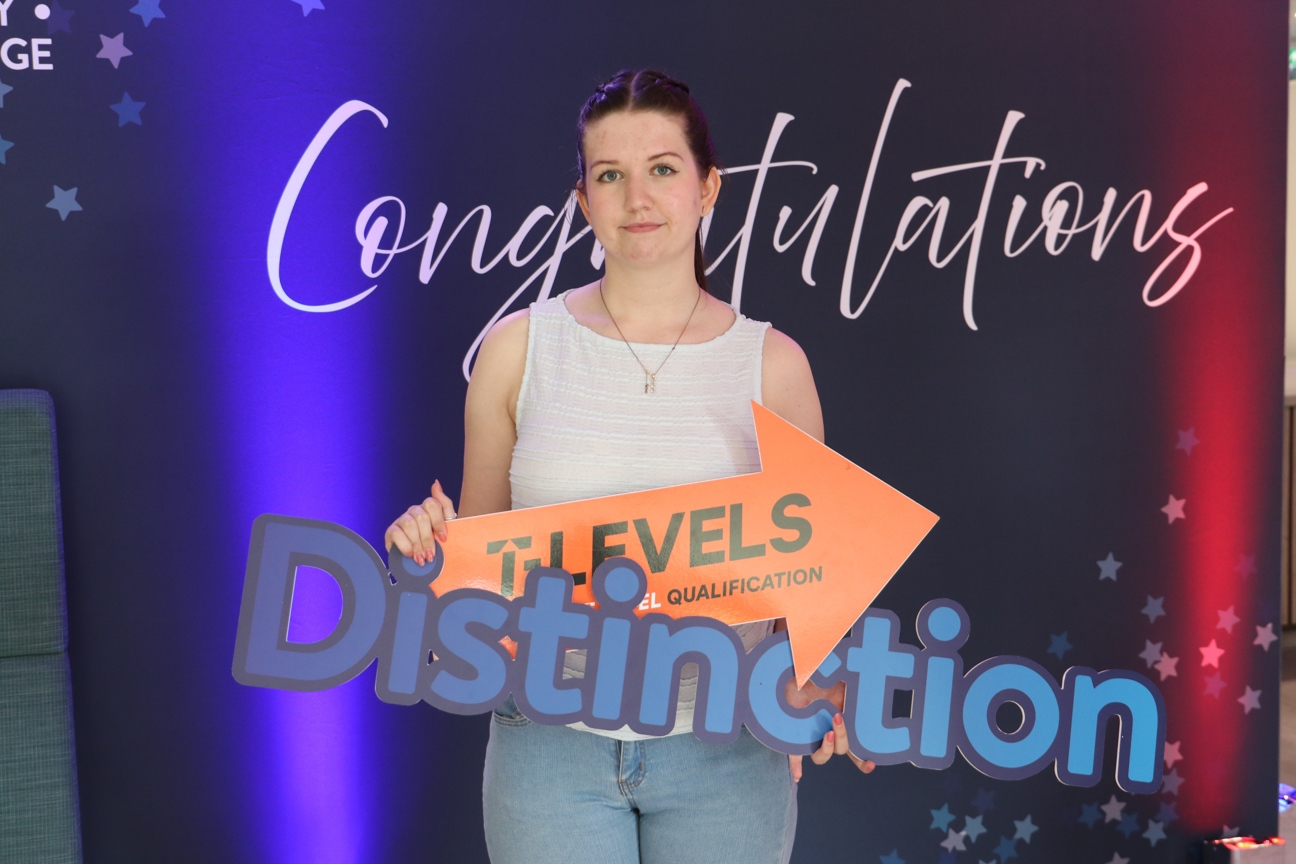 student on results day holding t level sign and distinction sign
