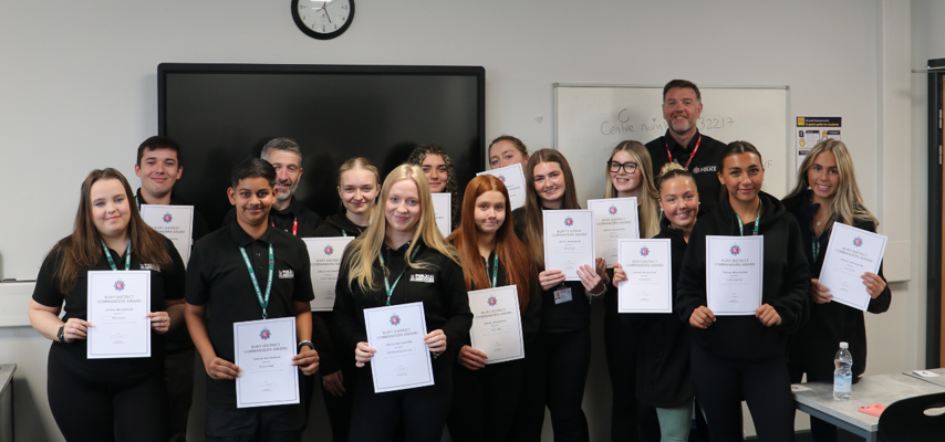 students all posing for a photo with greater manchester police whilst holding certificates