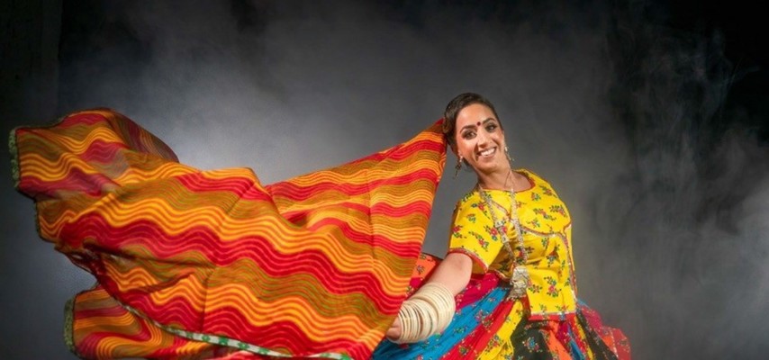 A photoshoot of a woman dancing, dressed in vibrant colourful clothes