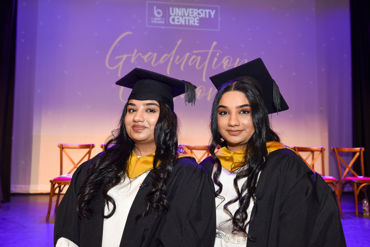 two students on graduation day in front of the stage