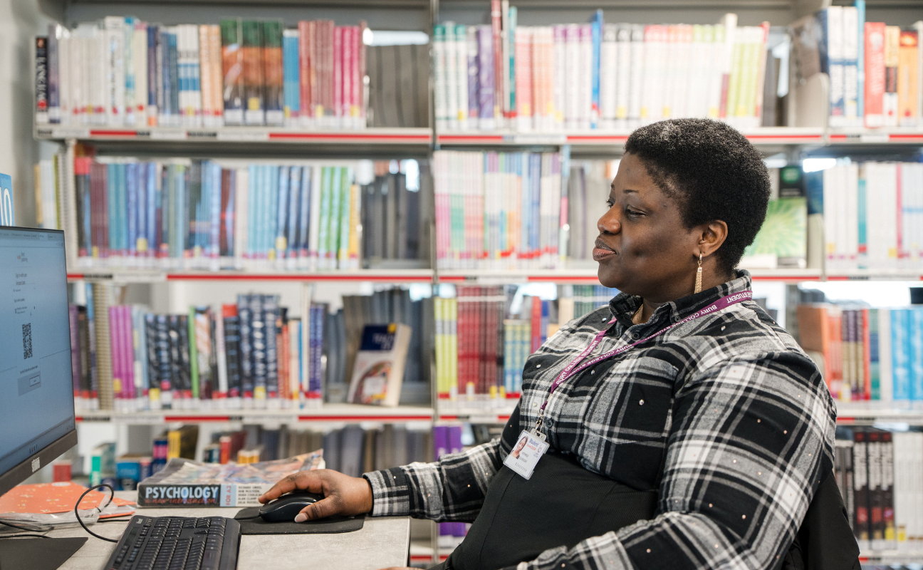 adult learner sat at a computer in the library