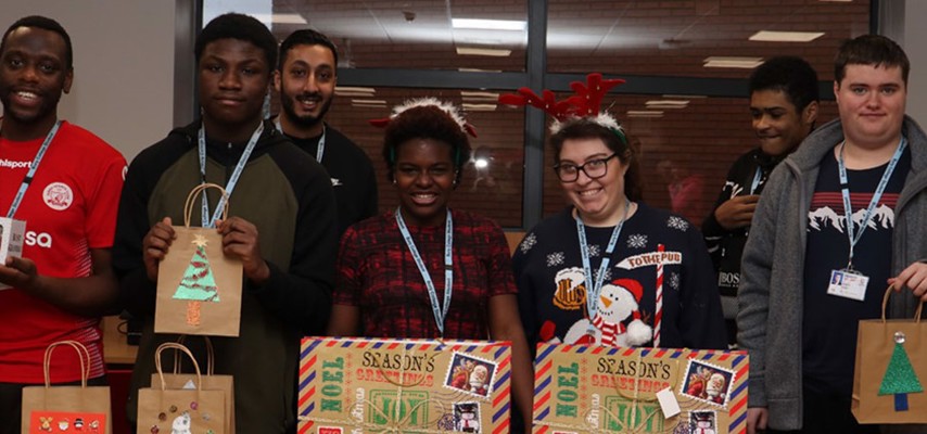 A group of Business Challenge students in front of wrapped Christmas gifts
