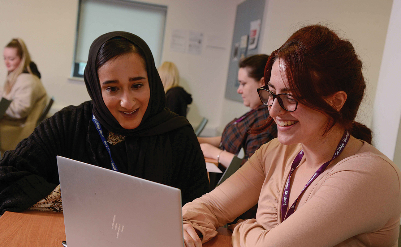 University student and tutor chatting to each other in a classroom