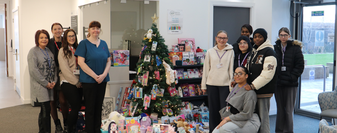 students and employers stood beside a Christmas tree with presents