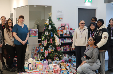 students and employers stood beside a Christmas tree with presents