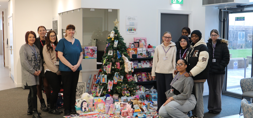 students and employers stood beside a Christmas tree with presents