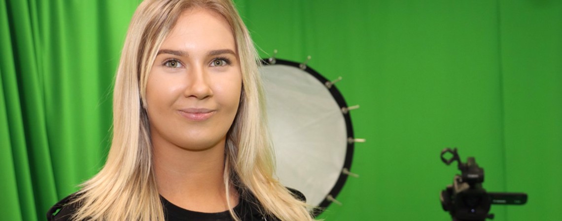 Former Creative Media Production student, Megan Barlow in front of a green screen studio