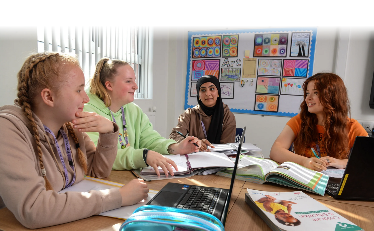 a group of four students sat in a classroom talking