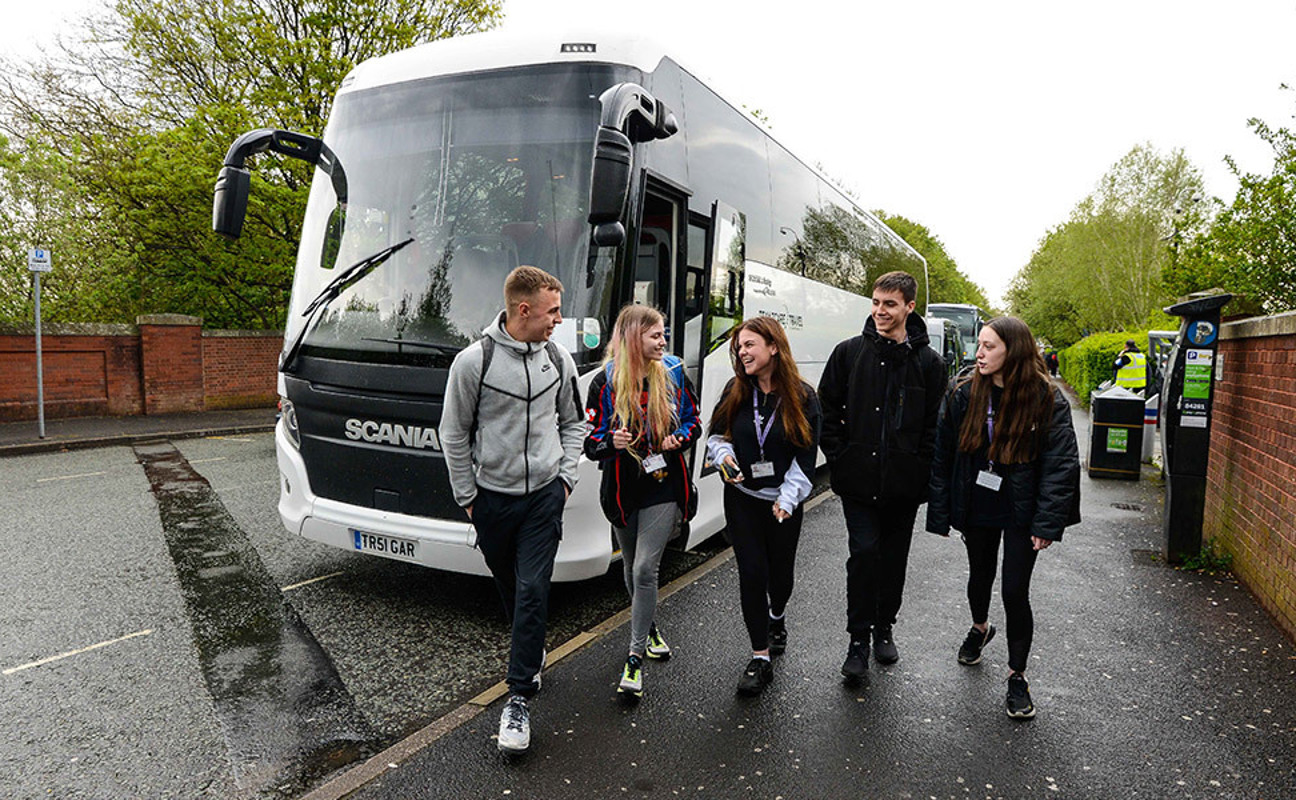 Students walking next to a coach
