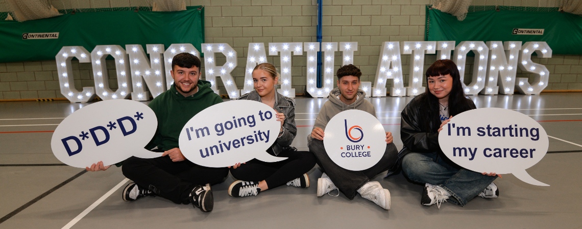 students sat in a row holding up boards sat in front of a congratulations sign