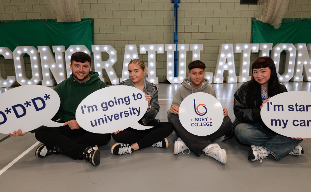 students sat in a row holding up boards sat in front of a congratulations sign