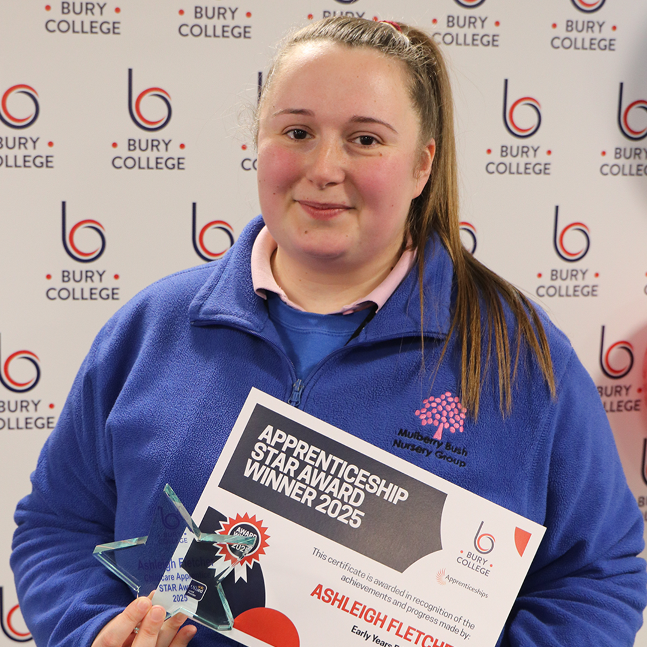 student holding glass trophy and certificate